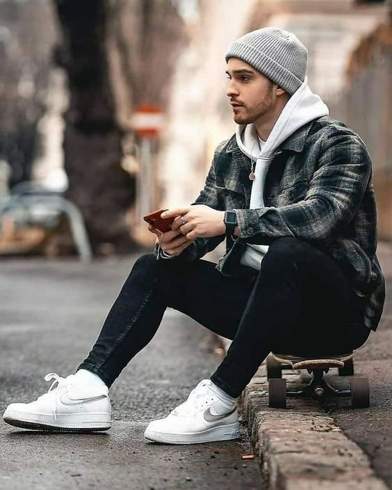 Person sitting on skateboard, using phone.