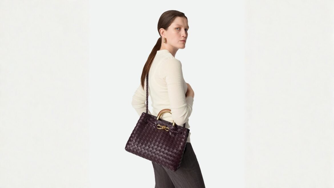 Woman holding a Bottega Veneta Andiamo handbag.