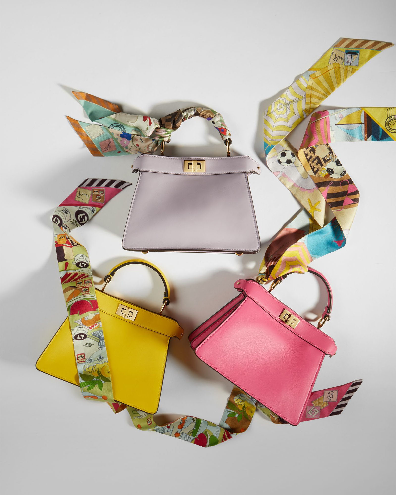 Three colourful Fendi leather top-handle bags styled with printed silk scarves.
