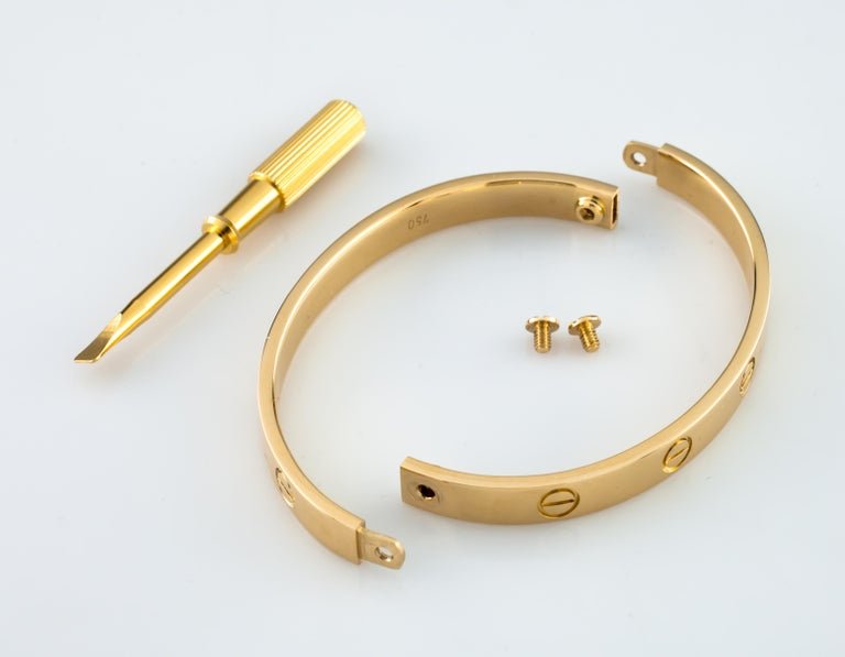 Cartier Love Bracelet shown in two rigid halves with its screws and screwdriver.
