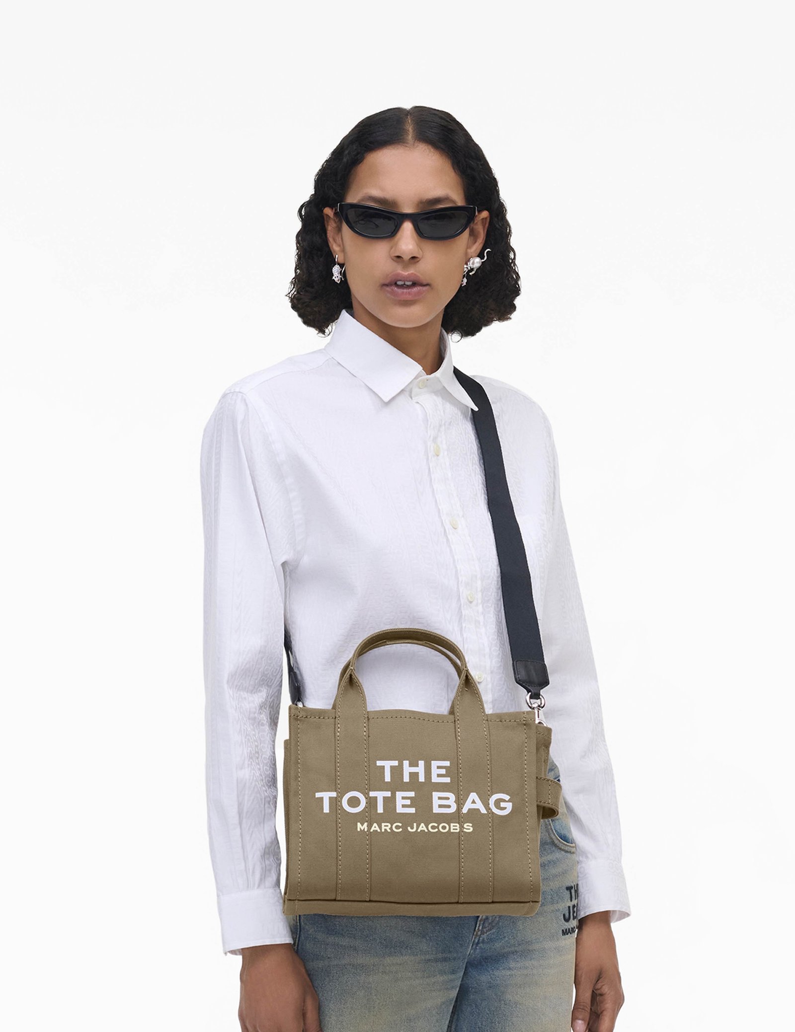 Model carrying a slate green Marc Jacobs Canvas Small Tote Bag with a white shirt and jeans.