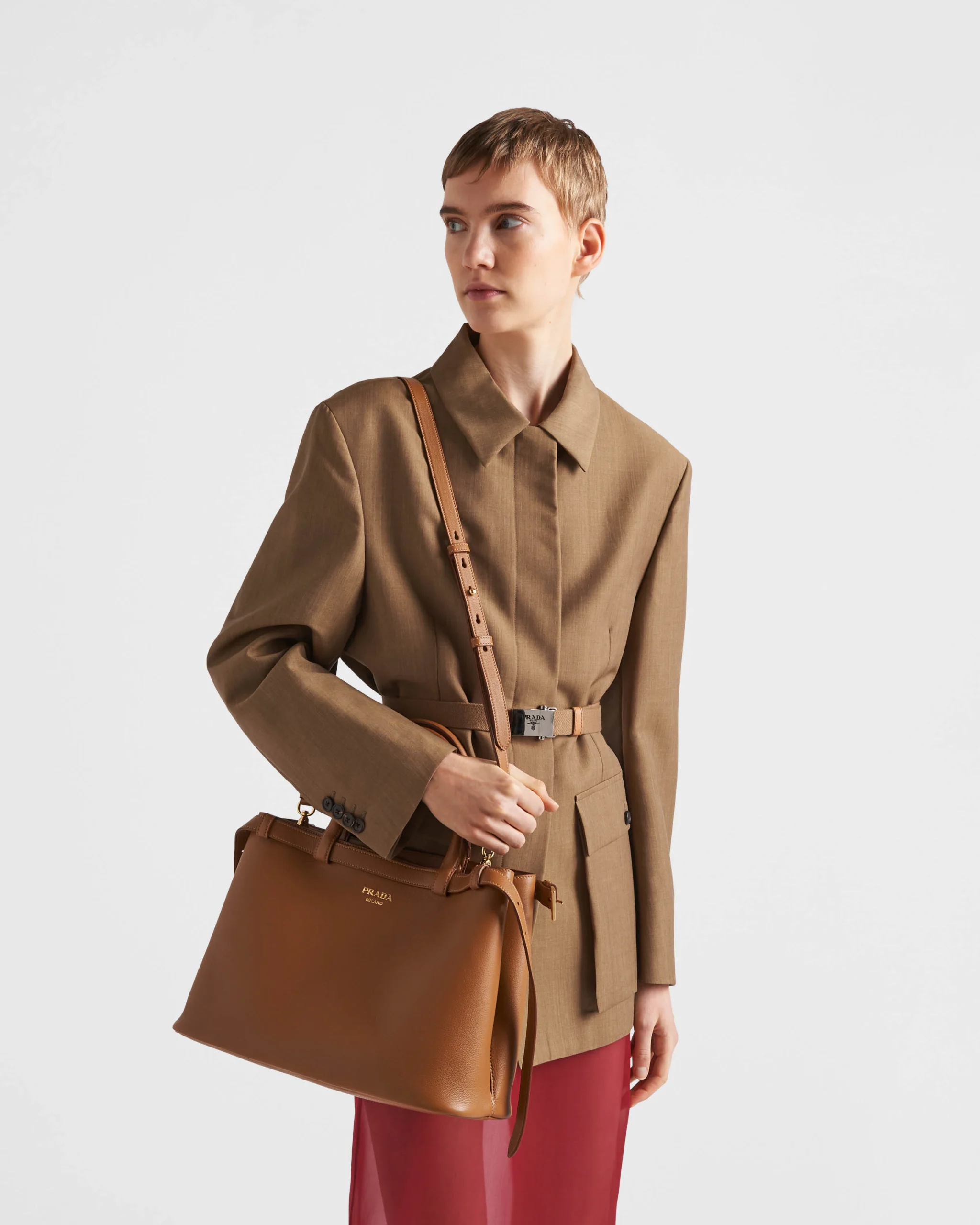 Model wearing the caramel medium Prada Buckle handbag over tailored separates.