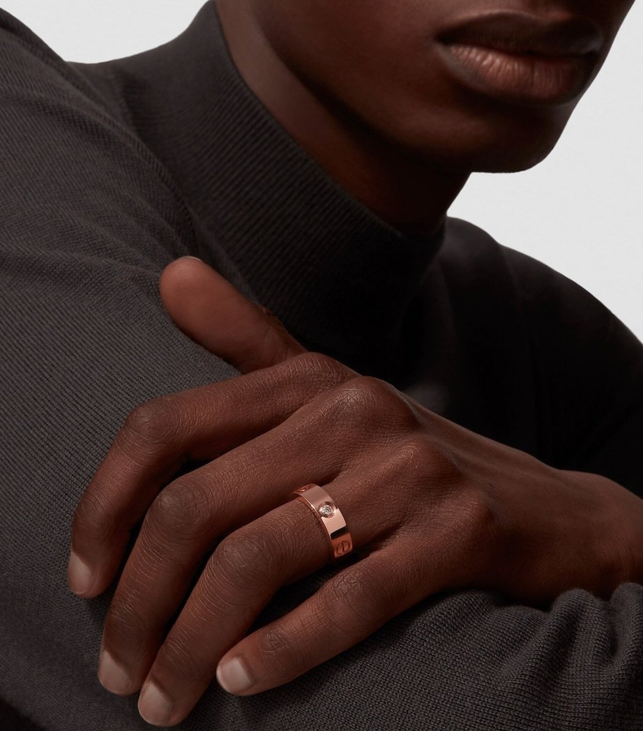 Model wearing a rose-gold Cartier LOVE ring with navy clothing.