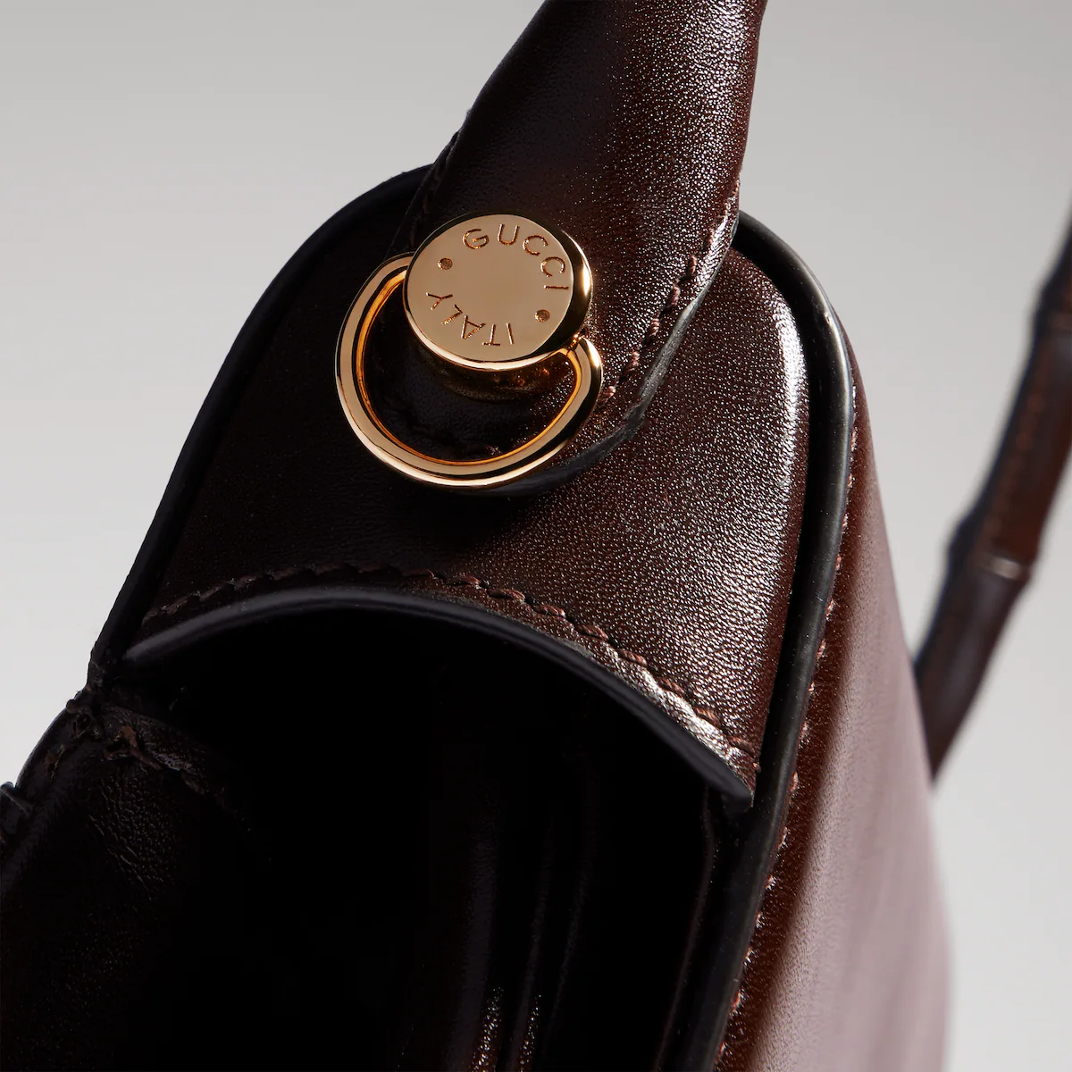 Close-up of the leather handle fastening on a dark brown Gucci Bamboo Vendetta.