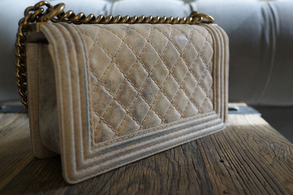 Pale quilted designer bag marked by blue denim dye transfer.