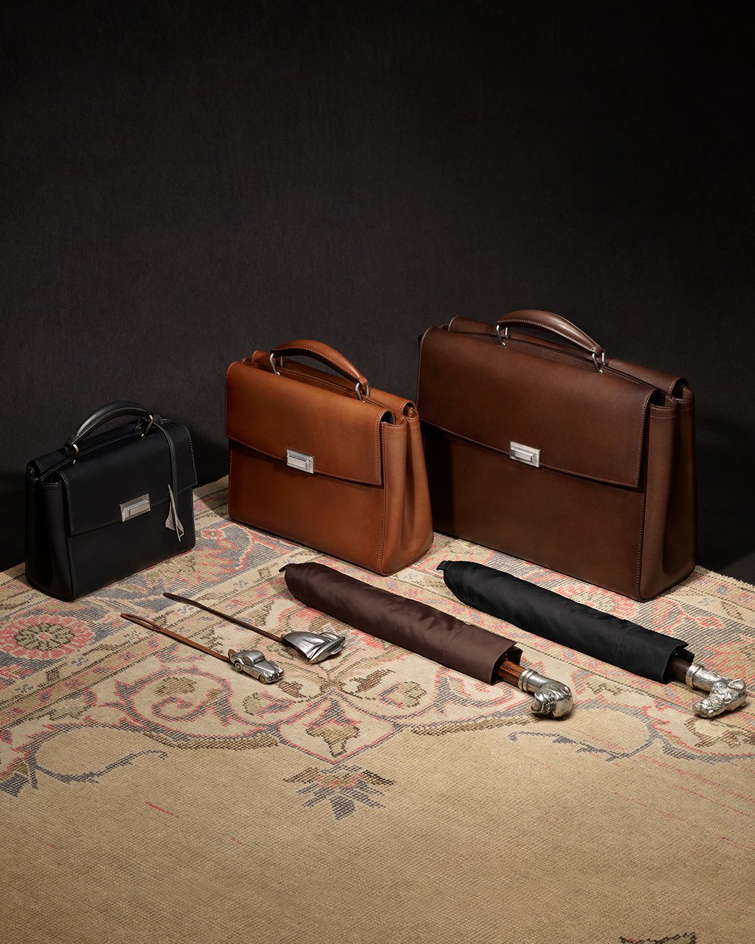Black, tan and brown Dunhill leather briefcases arranged together.