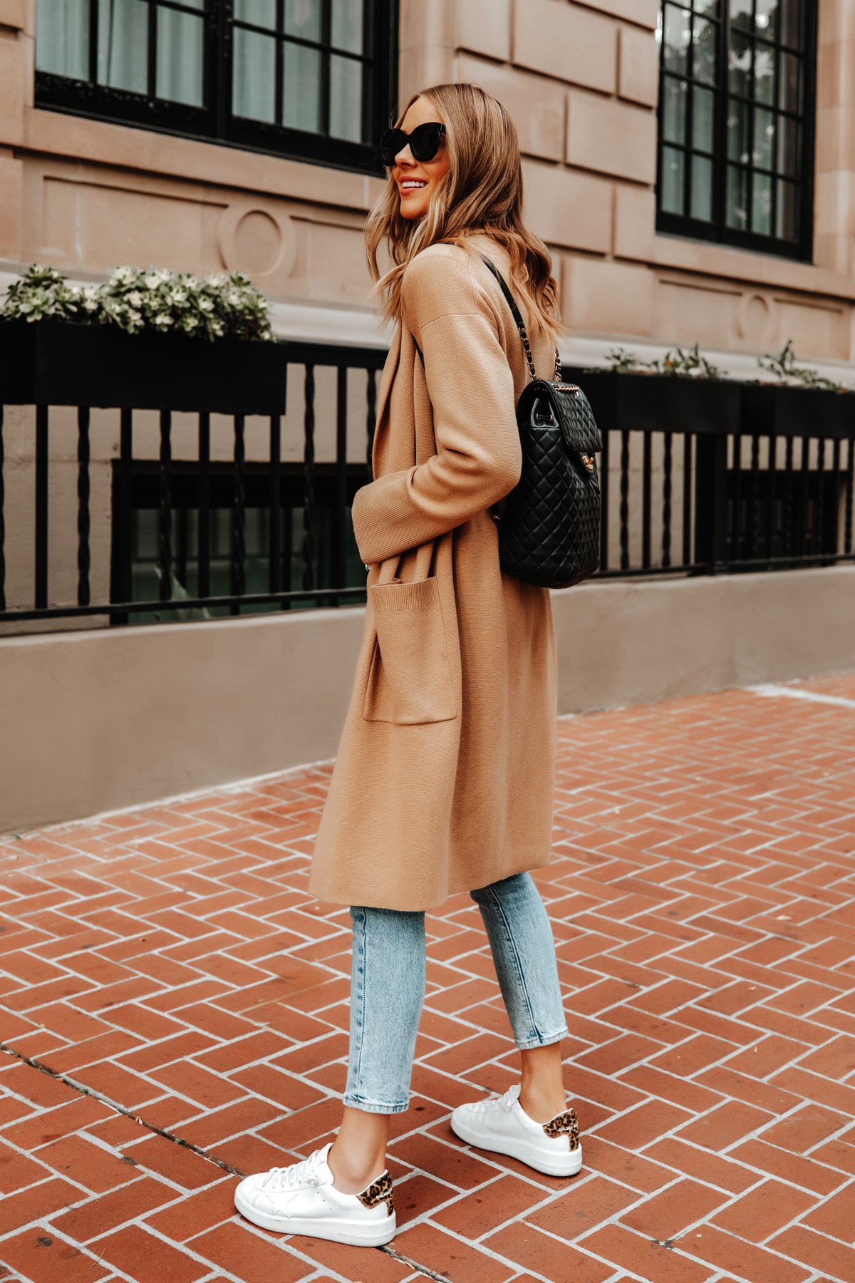 Model wearing Golden Goose sneakers with denim and a camel coat in a street-style outfit
