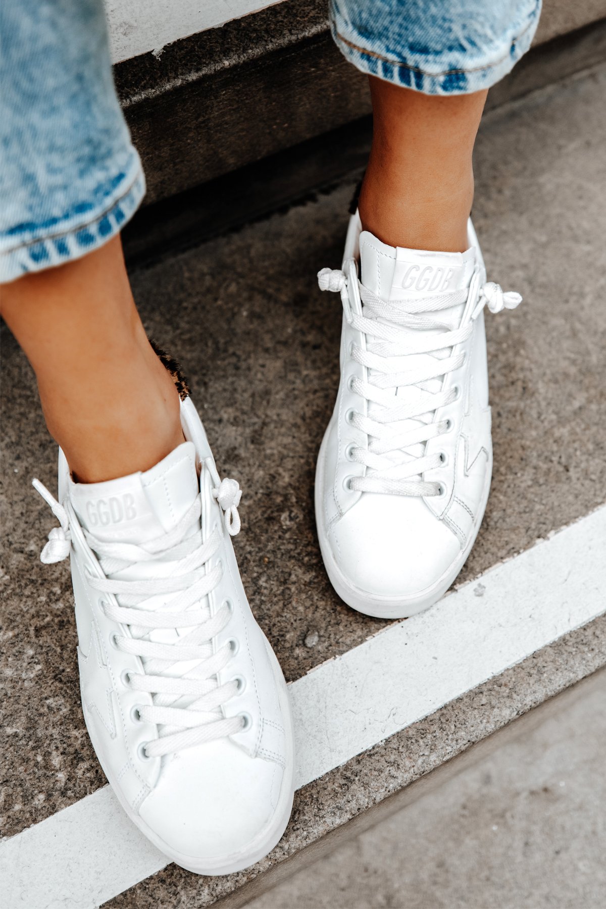Distressed white Golden Goose sneakers worn with straight-leg denim