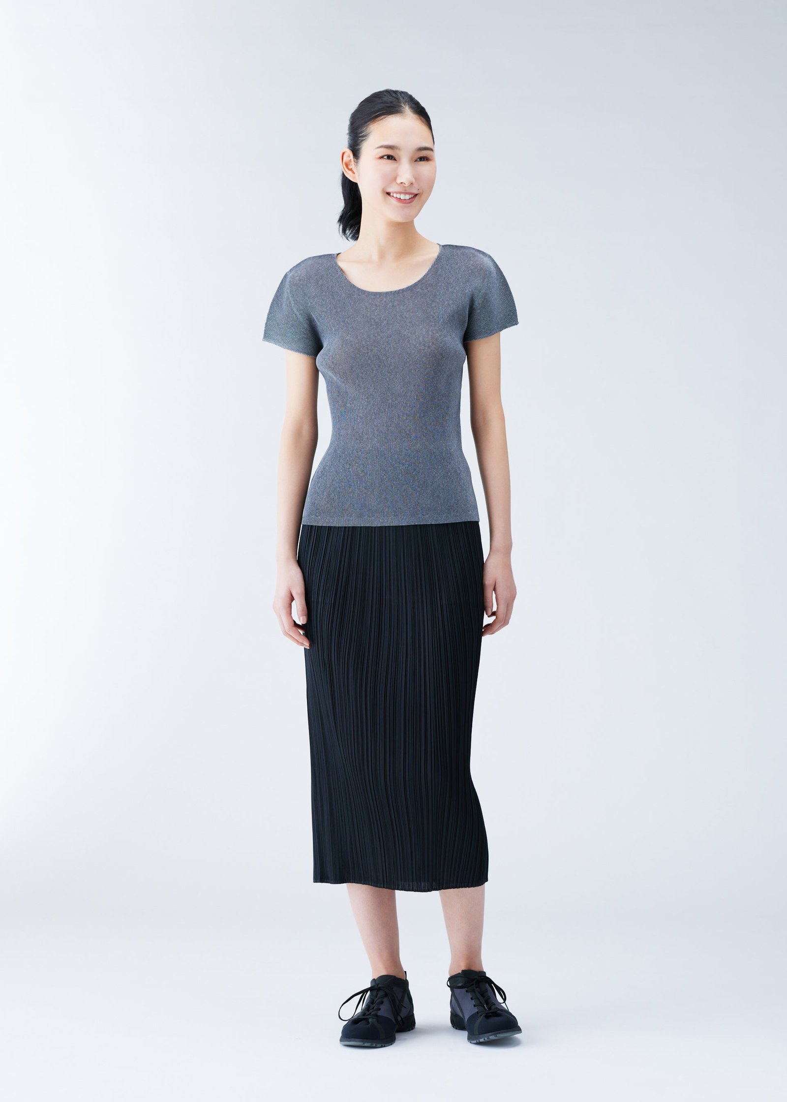Model wearing a Pleats Please Issey Miyake top with a pleated skirt