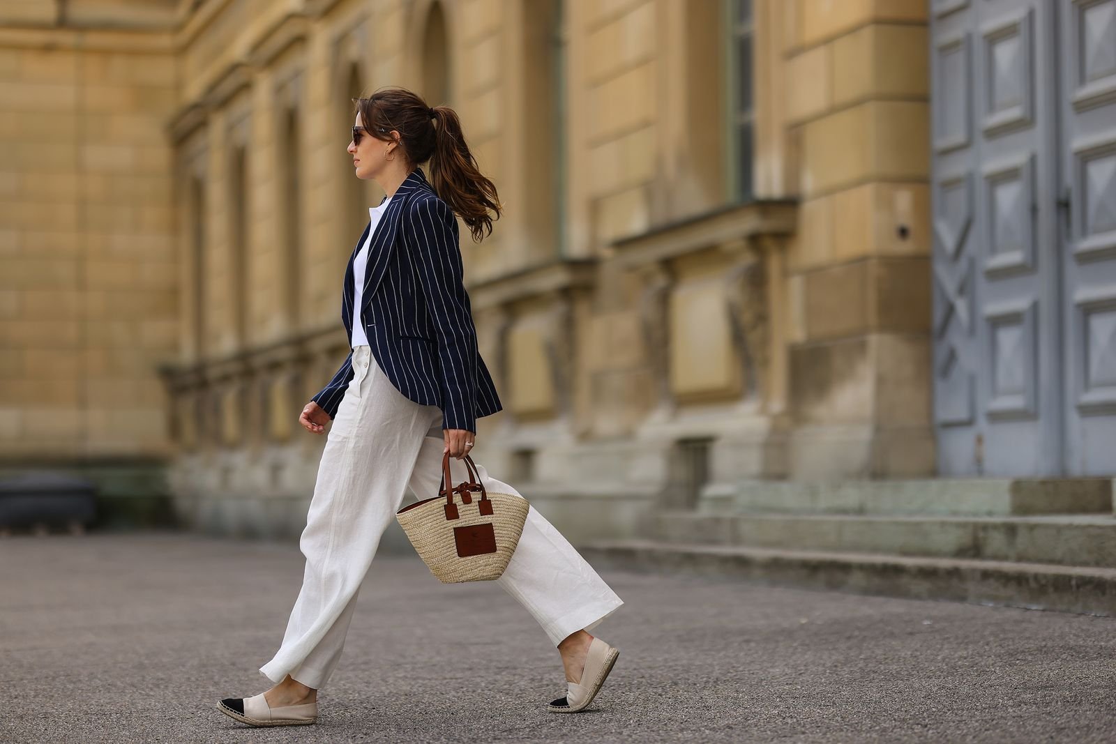 Model wearing Chanel espadrilles with a blazer and white summer trousers.