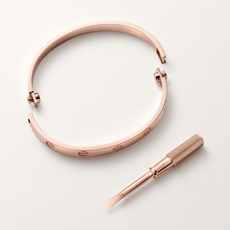 Open rose-gold Cartier Love Bracelet beside its screwdriver.