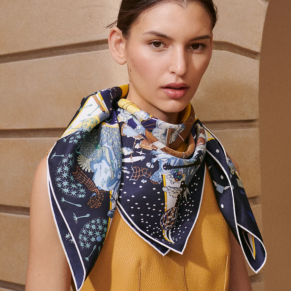 Model wearing a blue Hermès Carré 90 silk scarf draped around her neck.