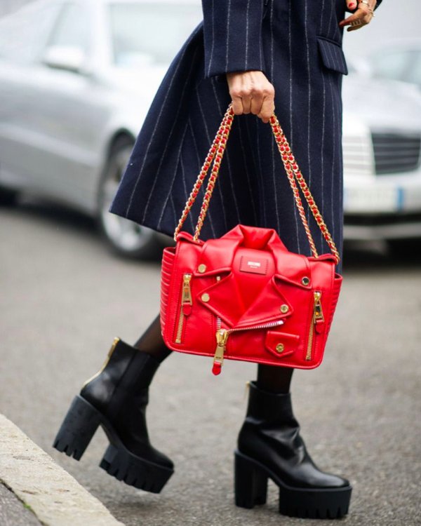 Street-style model carrying a red Moschino Biker Jacket Bag with a dark tailored coat.