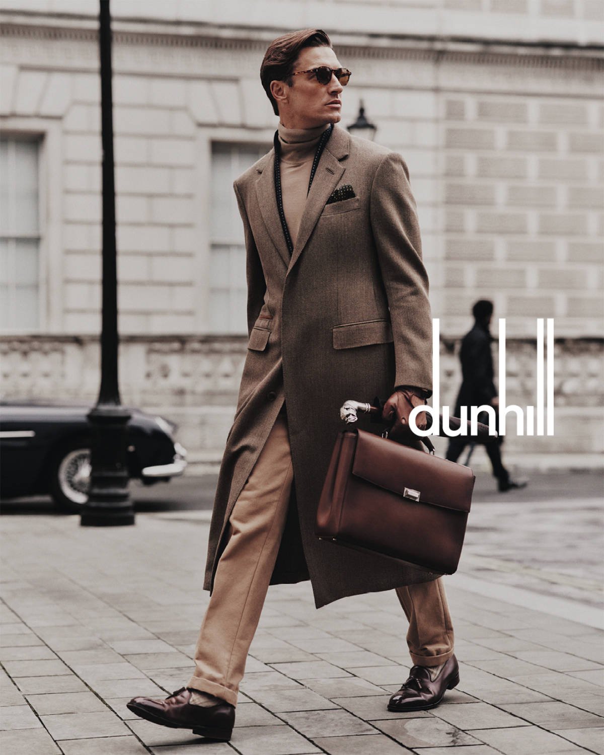 Model carrying Dunhill leather goods with tailored clothing in London.