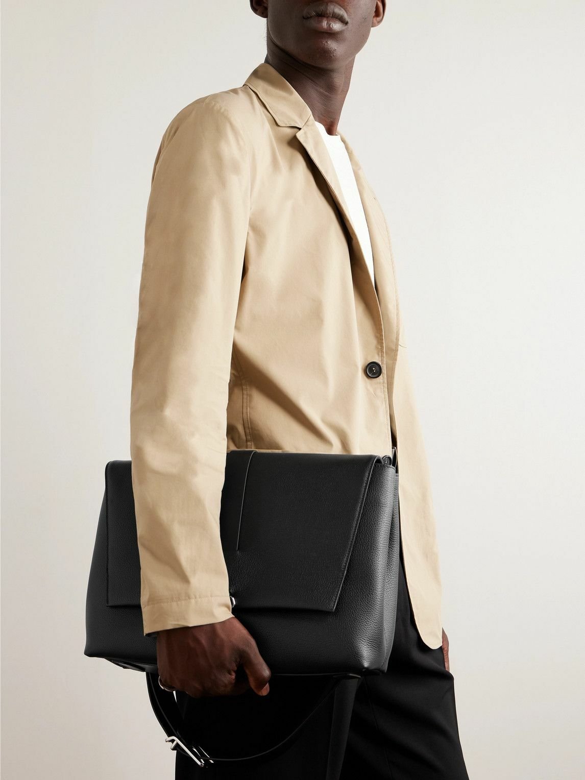 Model carrying a brown full-grain leather Dunhill messenger bag.