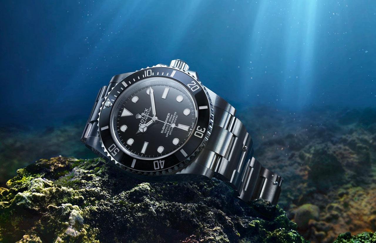 Black Rolex Submariner displayed underwater on coastal rock.