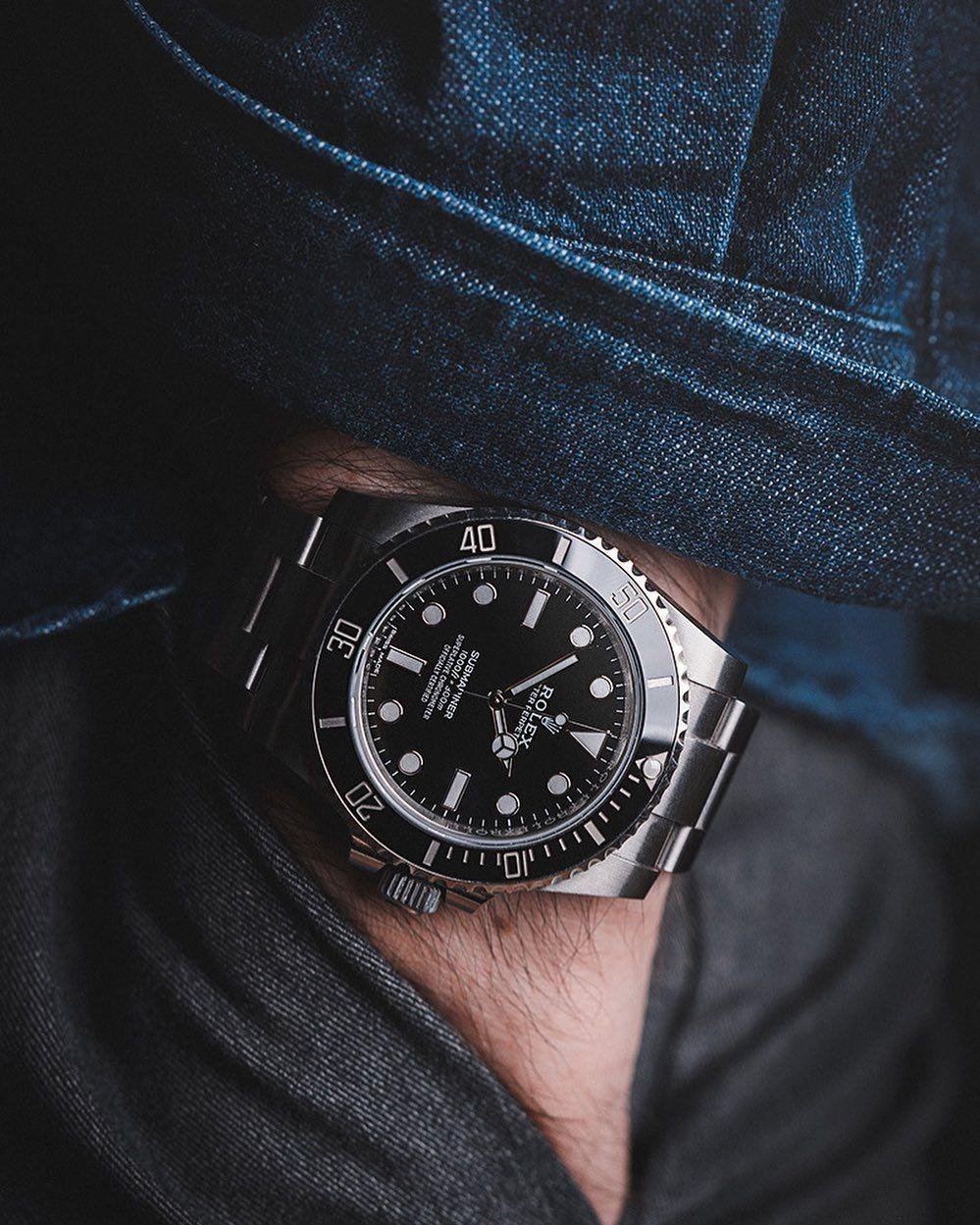 Model wearing a Rolex Submariner with a denim jacket and white shirt.