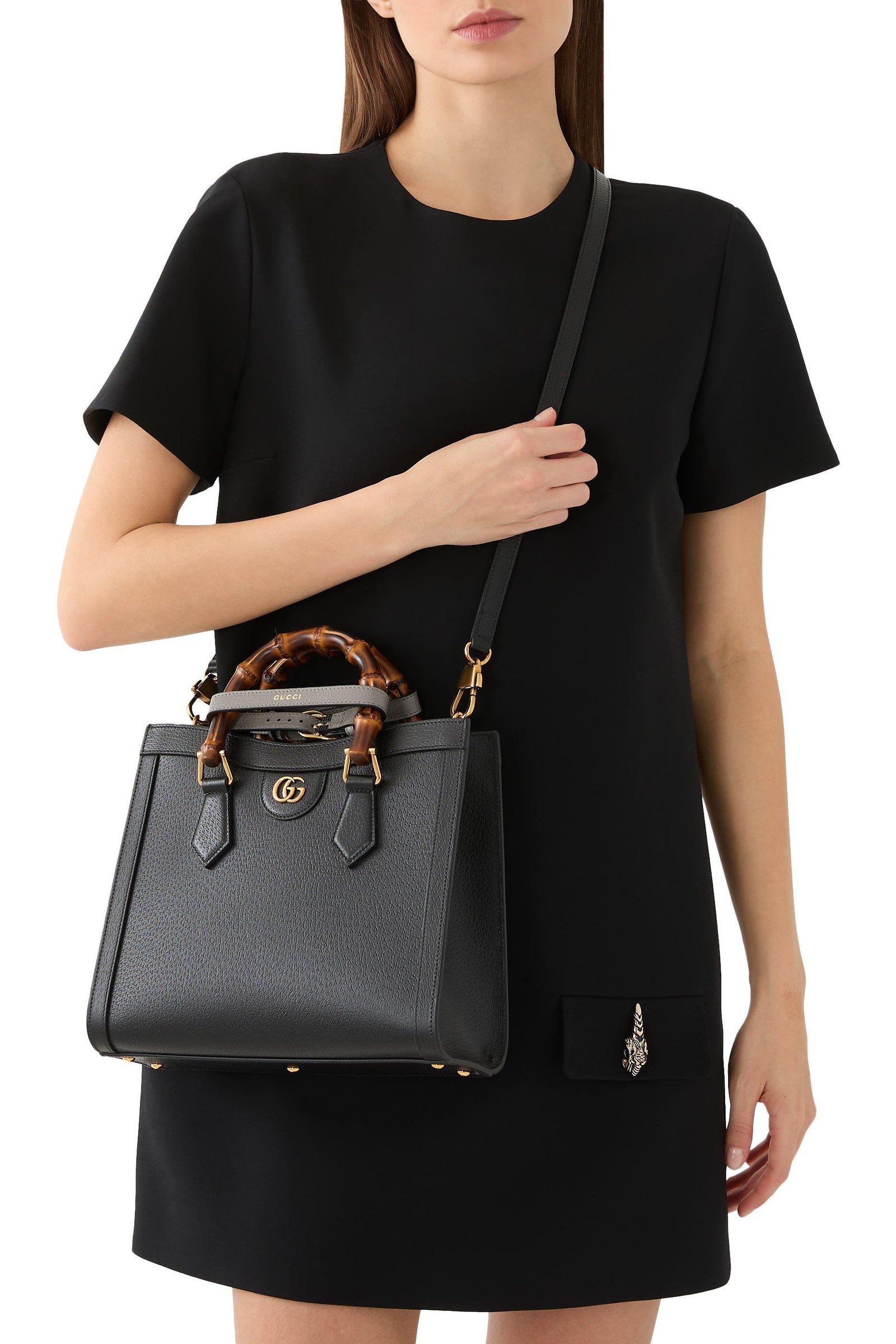 Model carrying a black Gucci Diana tote by its bamboo handles.