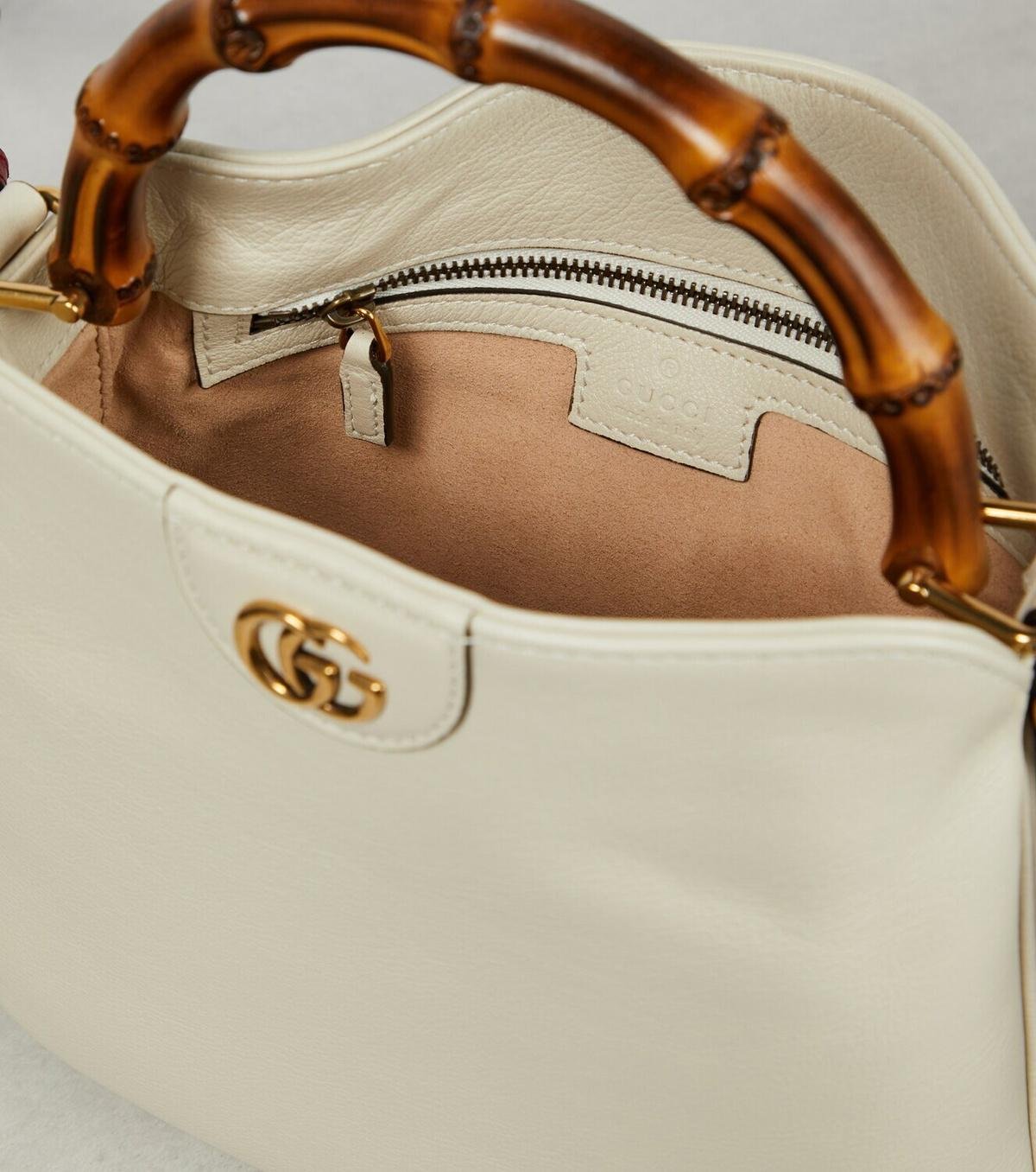 Close view of a cream Gucci Diana bag with bamboo handles and leather trim.