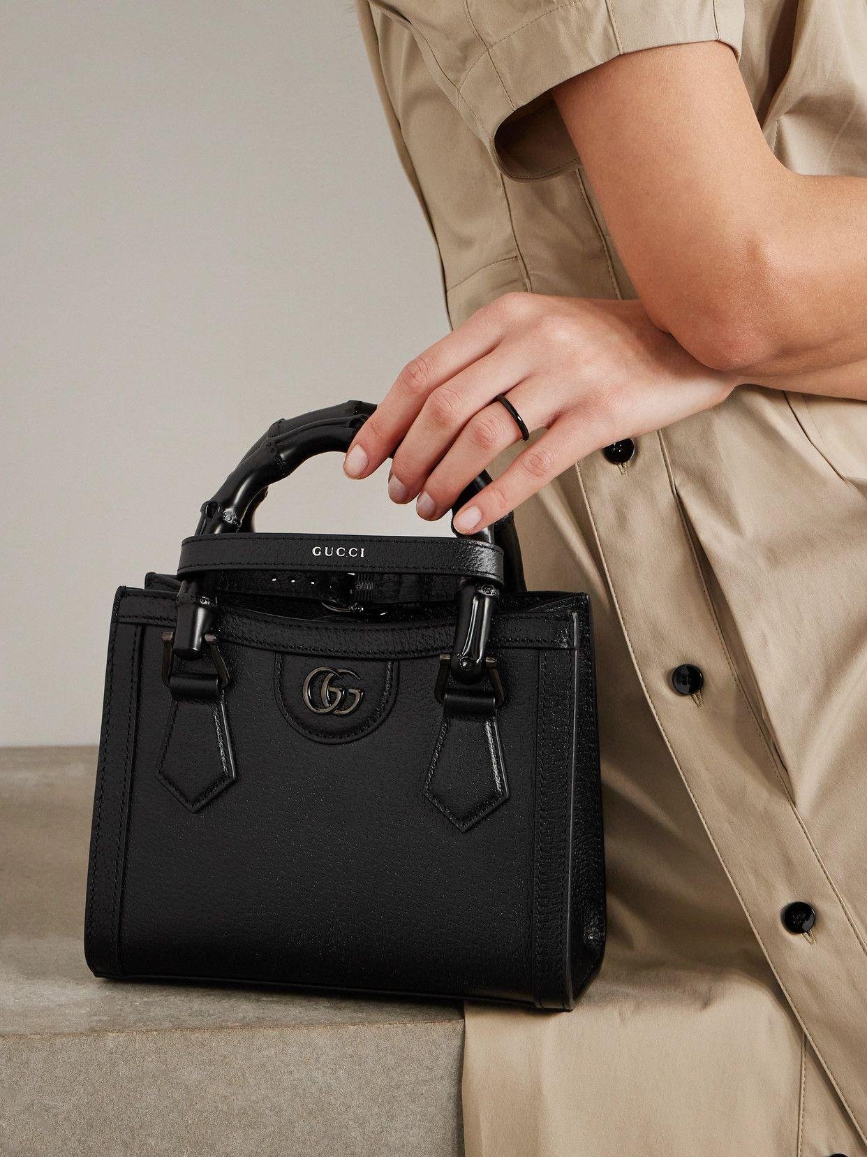 Black Gucci Diana bag carried by hand to show its structured proportions.