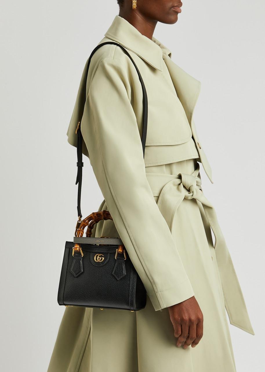 Model styling a black Gucci Diana bag with a green trench coat.