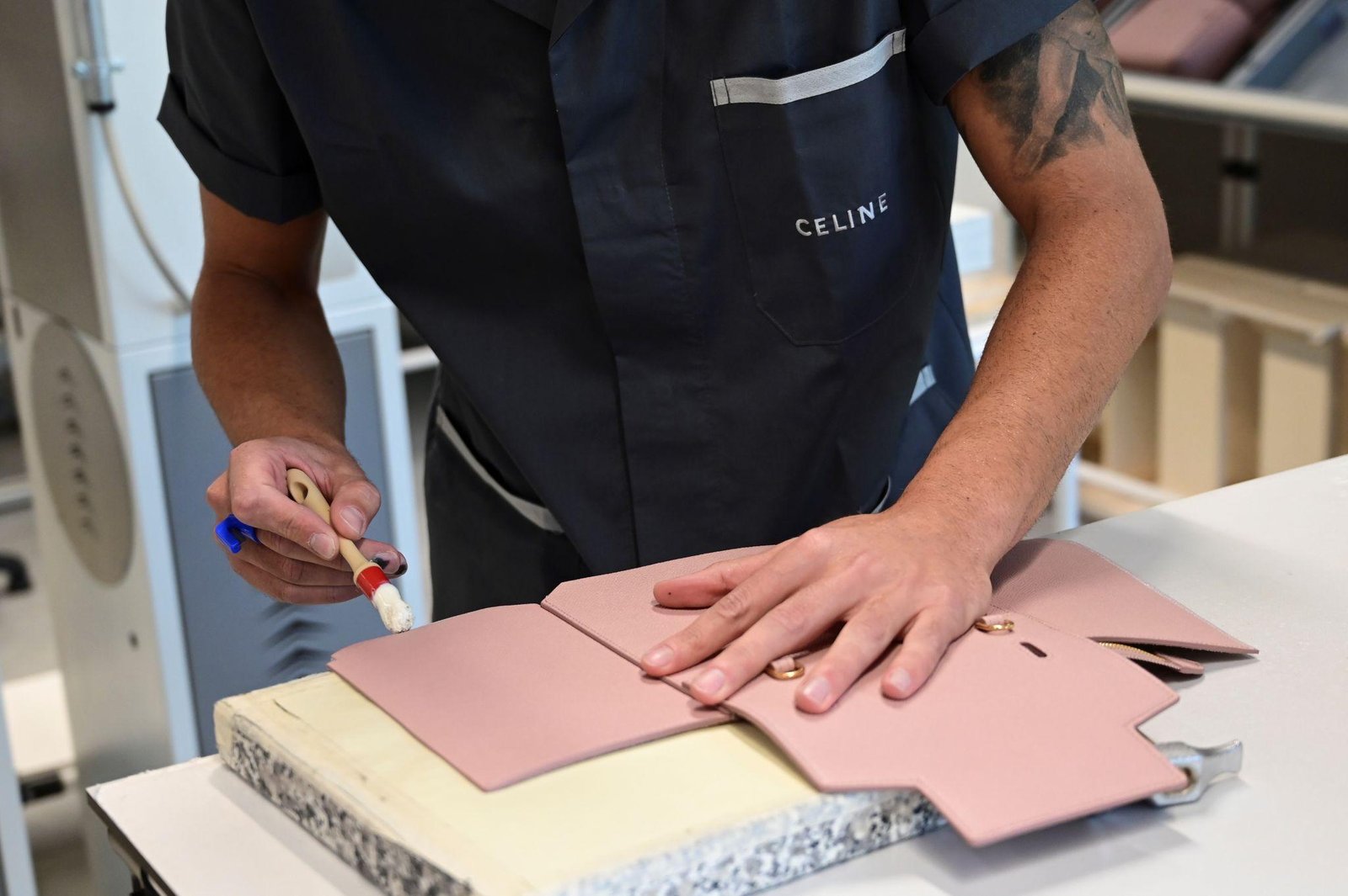 Artisan working with leather components during Celine Triomphe bag construction.