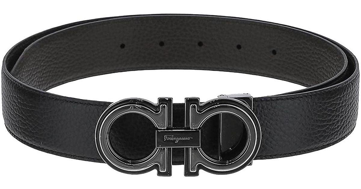 Black Ferragamo men’s belt with a dark Gancini buckle on a stone surface.