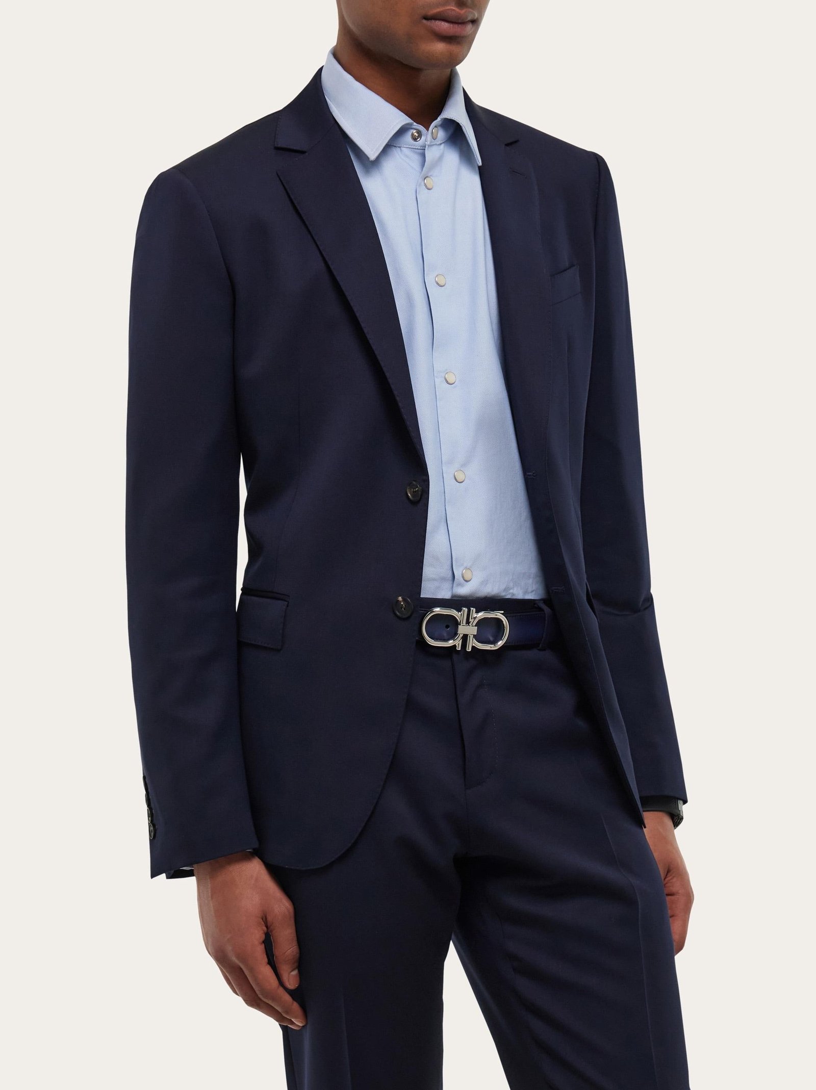 Man styling a Ferragamo belt with a navy suit and open-collar shirt.