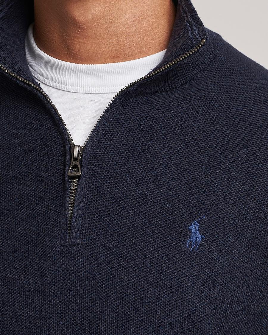 Model wearing a green Polo Ralph Lauren quarter-zip sweater with beige trousers.