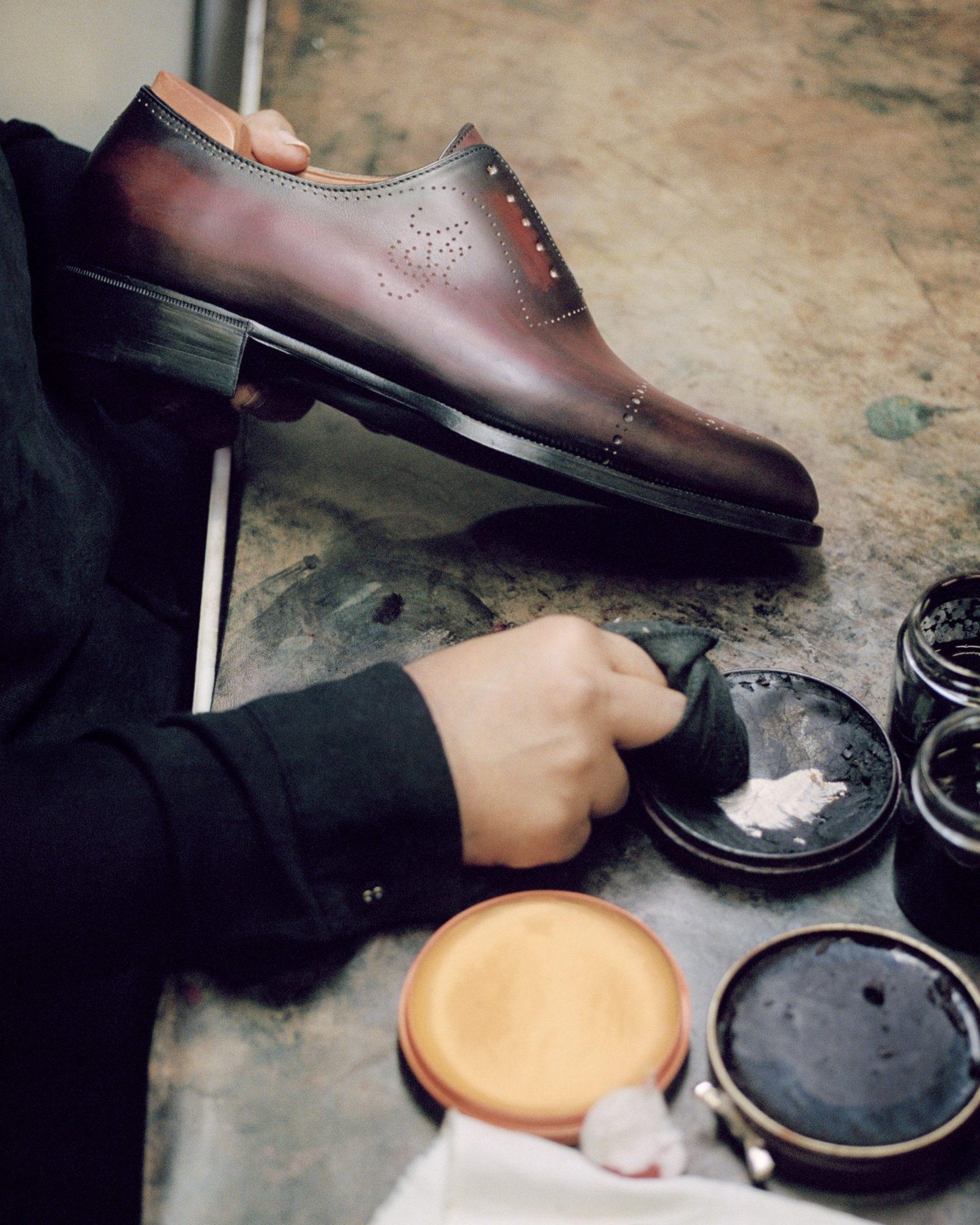 Berluti leather shoes being maintained with wax and wooden shoe trees.