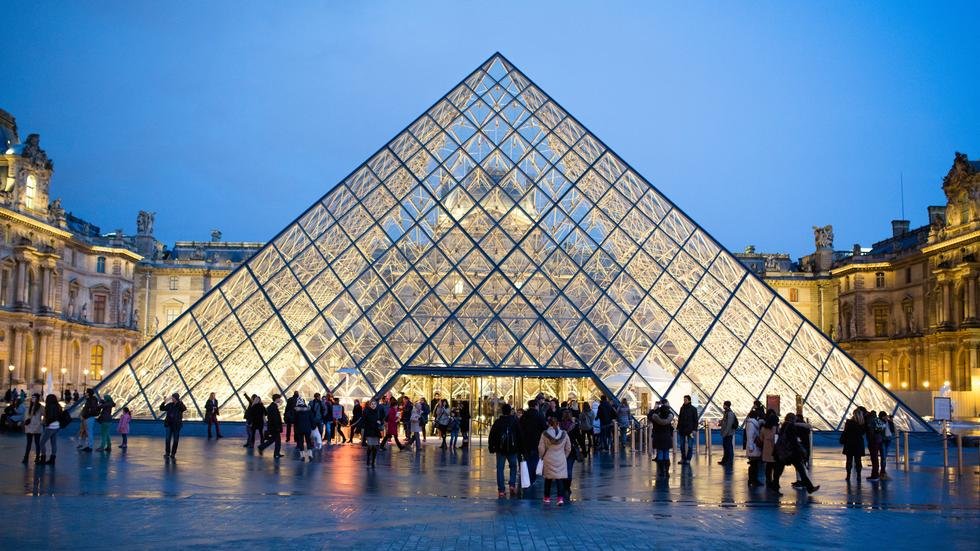 Visitors entering the Louvre Pyramid during the evening.