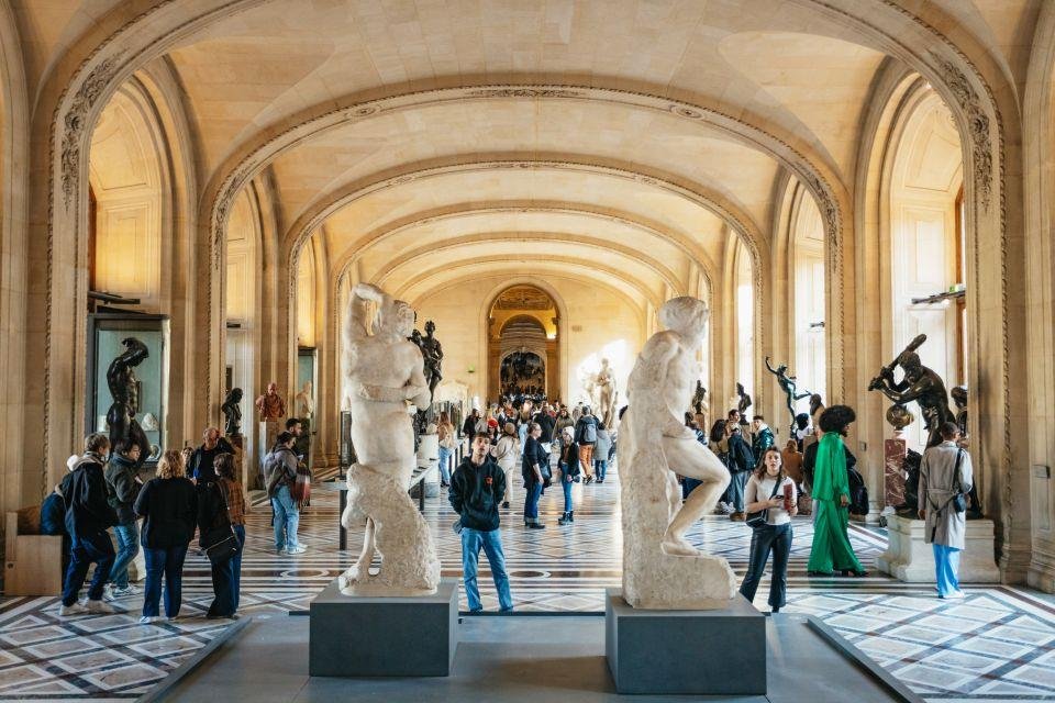 Visitors viewing sculptures inside the Louvre Museum.