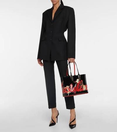 Model styling black Christian Louboutin pumps with a tailored black suit.