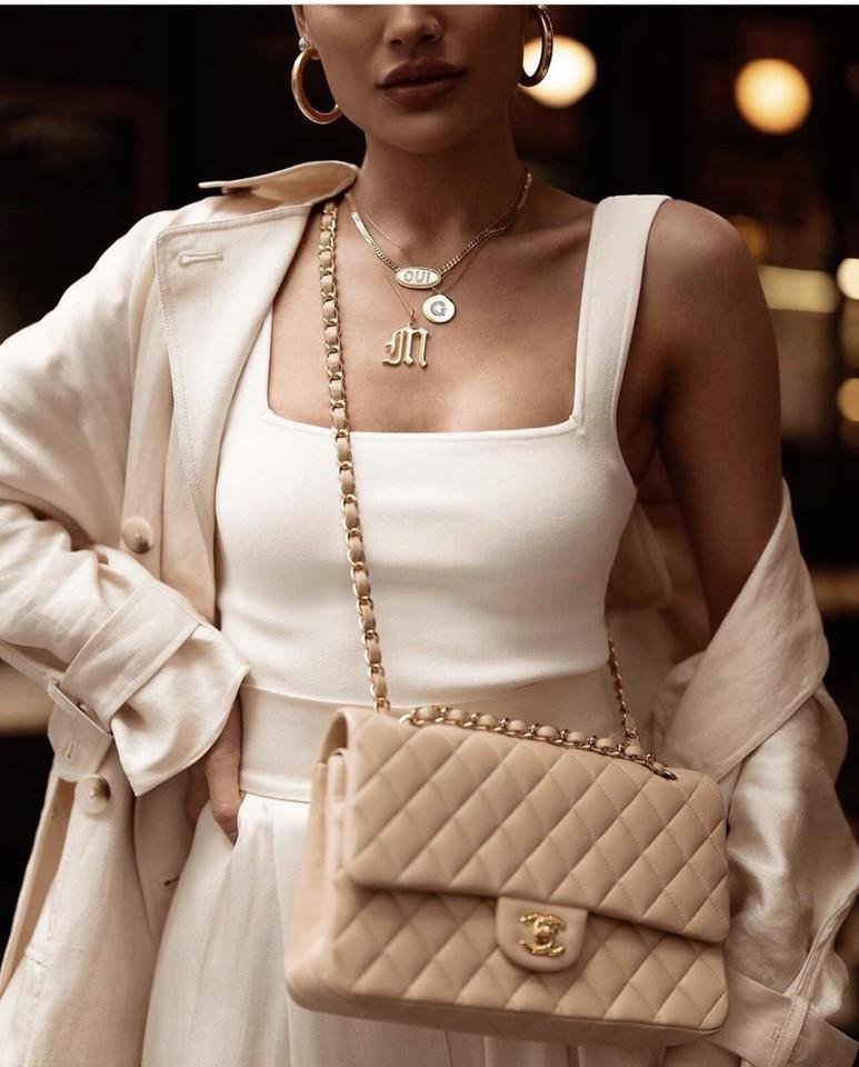 Model styling a pale Chanel Classic Flap with an elegant neutral outfit.