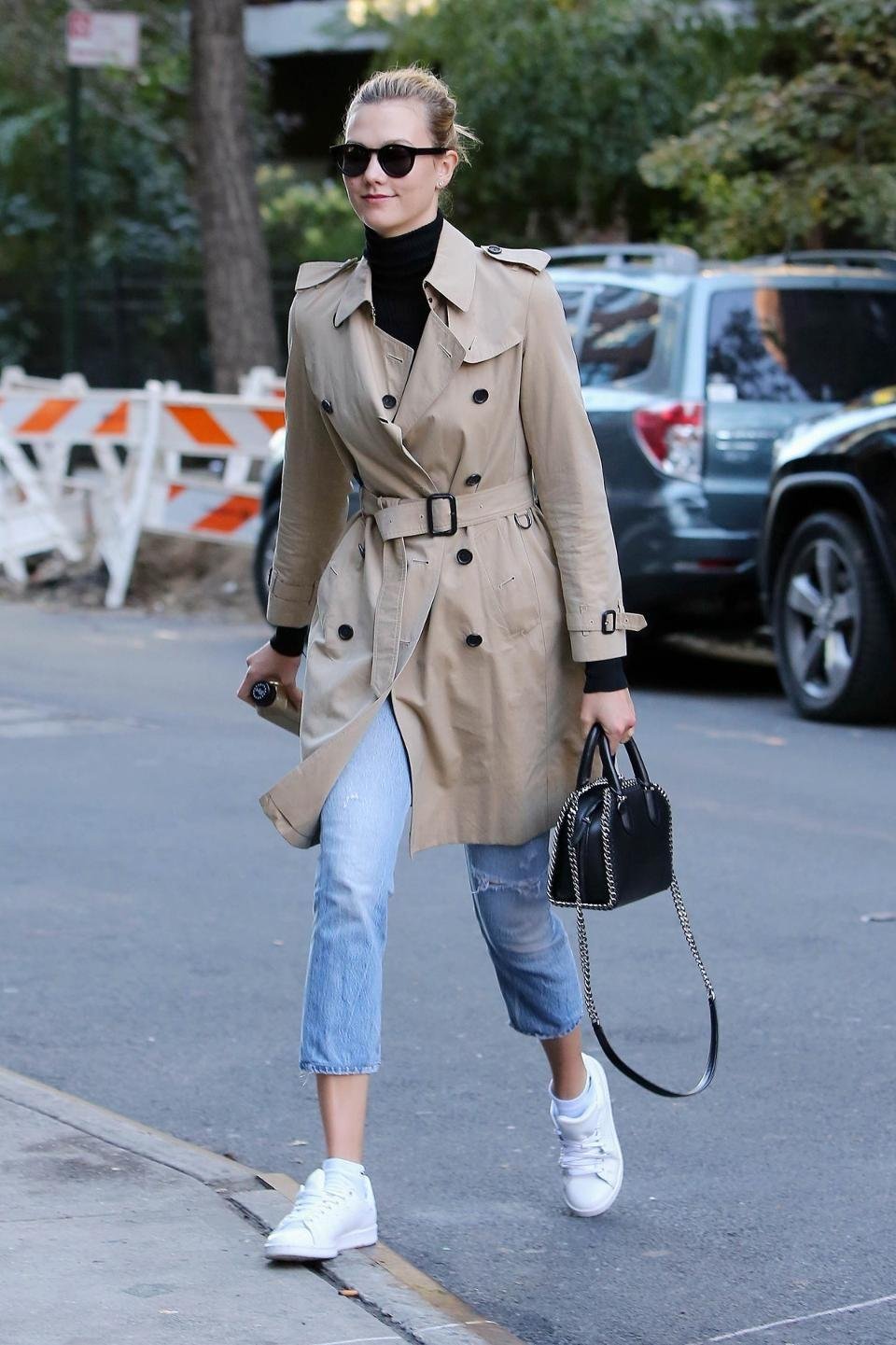 Woman styling a belted Burberry trench coat with jeans and flat shoes.