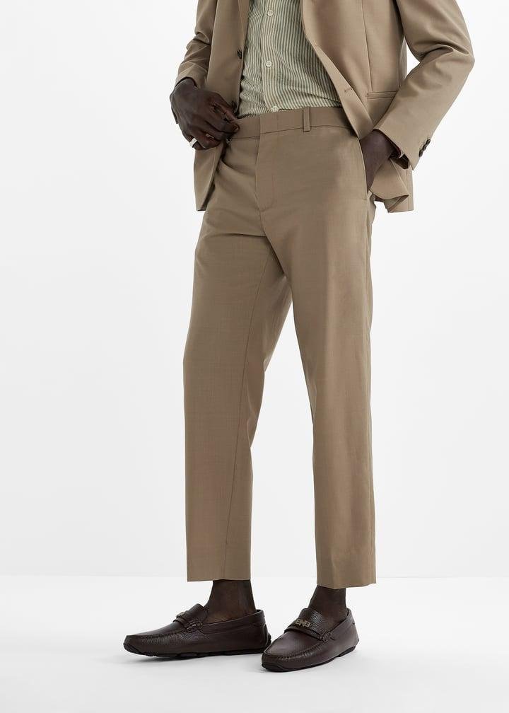 Model styling dark Bally shoes with a neutral tailored outfit.