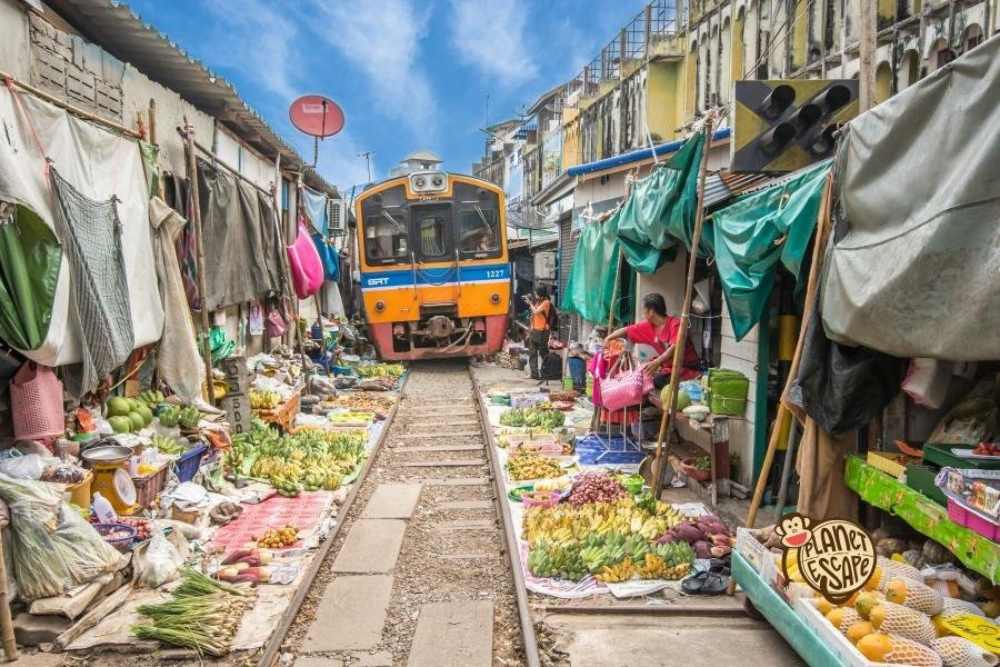 Train passing between market stalls at Maeklong Railway Market in Thailand.