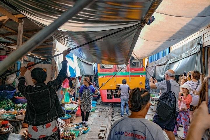 Market vendors folding awnings beside the railway at Maeklong.