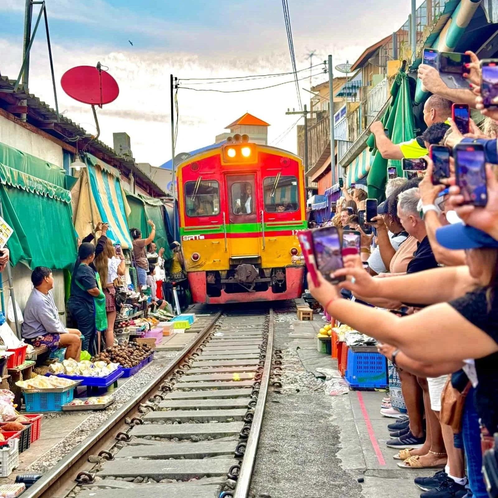Passenger train travelling through Maeklong Railway Market.
