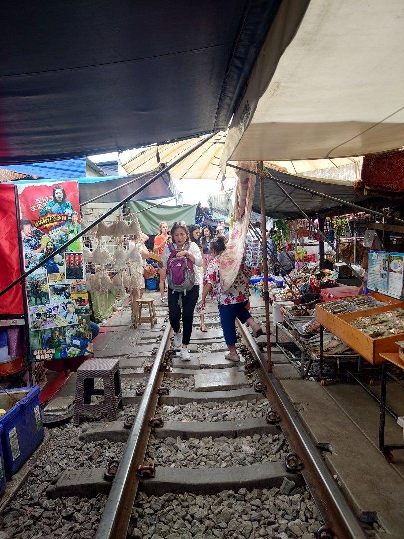 Travellers walking between stalls at Maeklong Railway Market.
