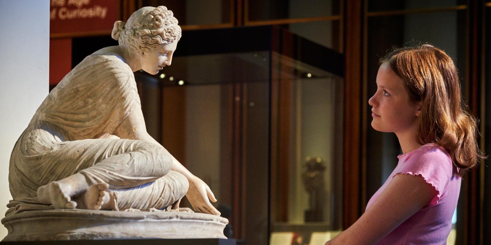 Visitor examining an ancient sculpture at the British Museum