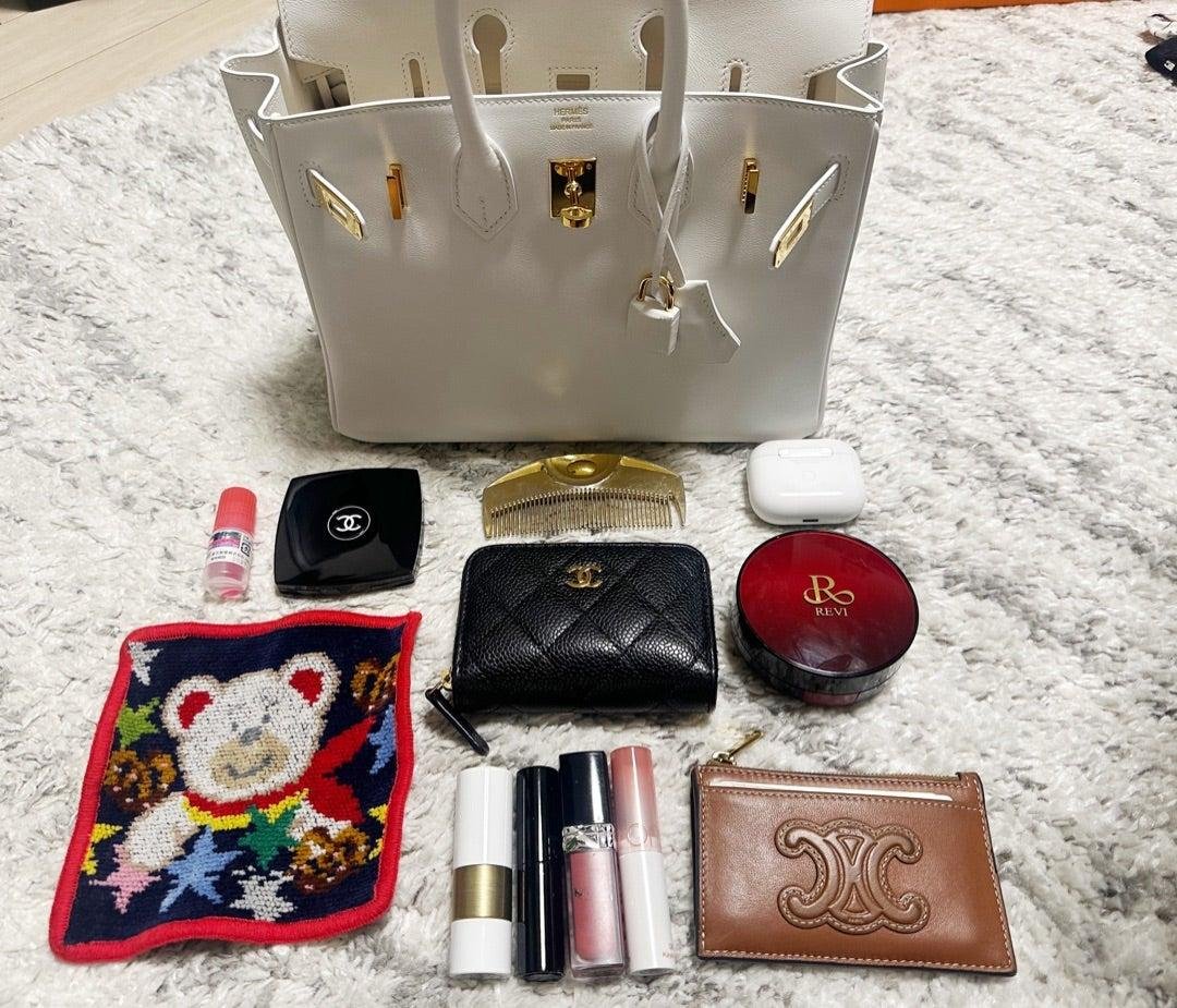 Everyday essentials arranged inside Hermès Birkin bags.