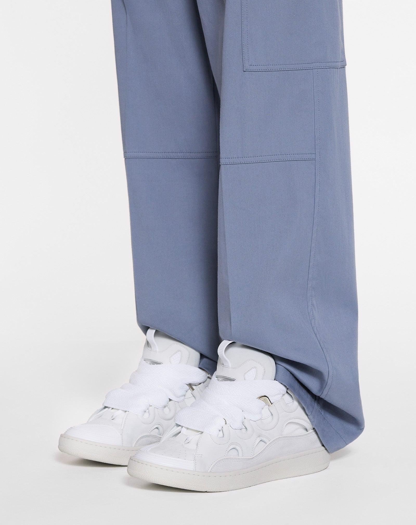 White Lanvin sneakers worn with blue tailored trousers