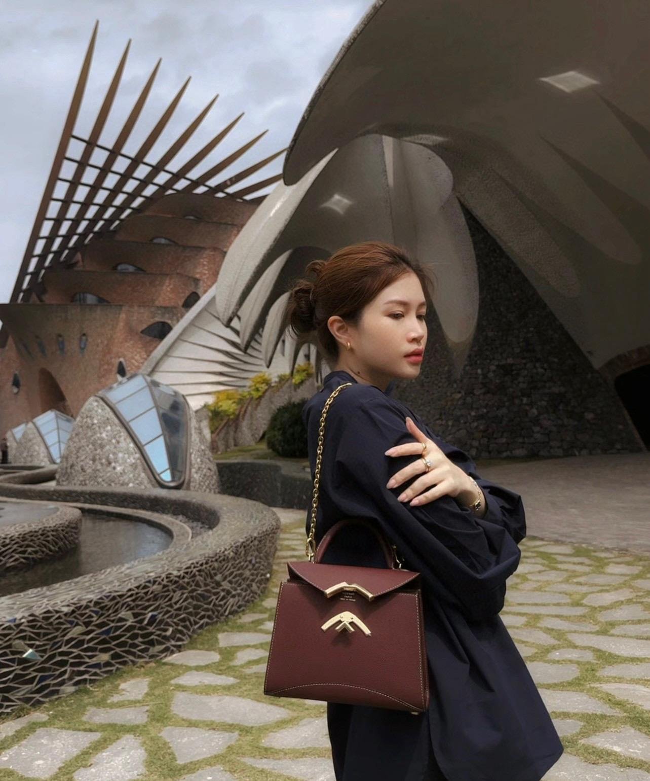 Model wearing a Moynat Gabrielle bag with a dark outfit.