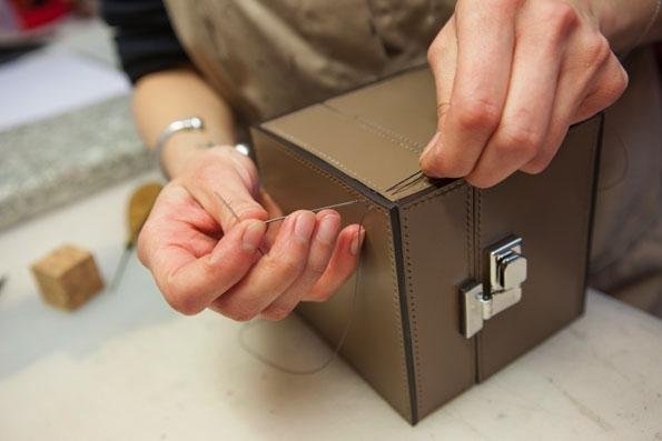 Artisan working on the metal closure of a Moynat leather bag.