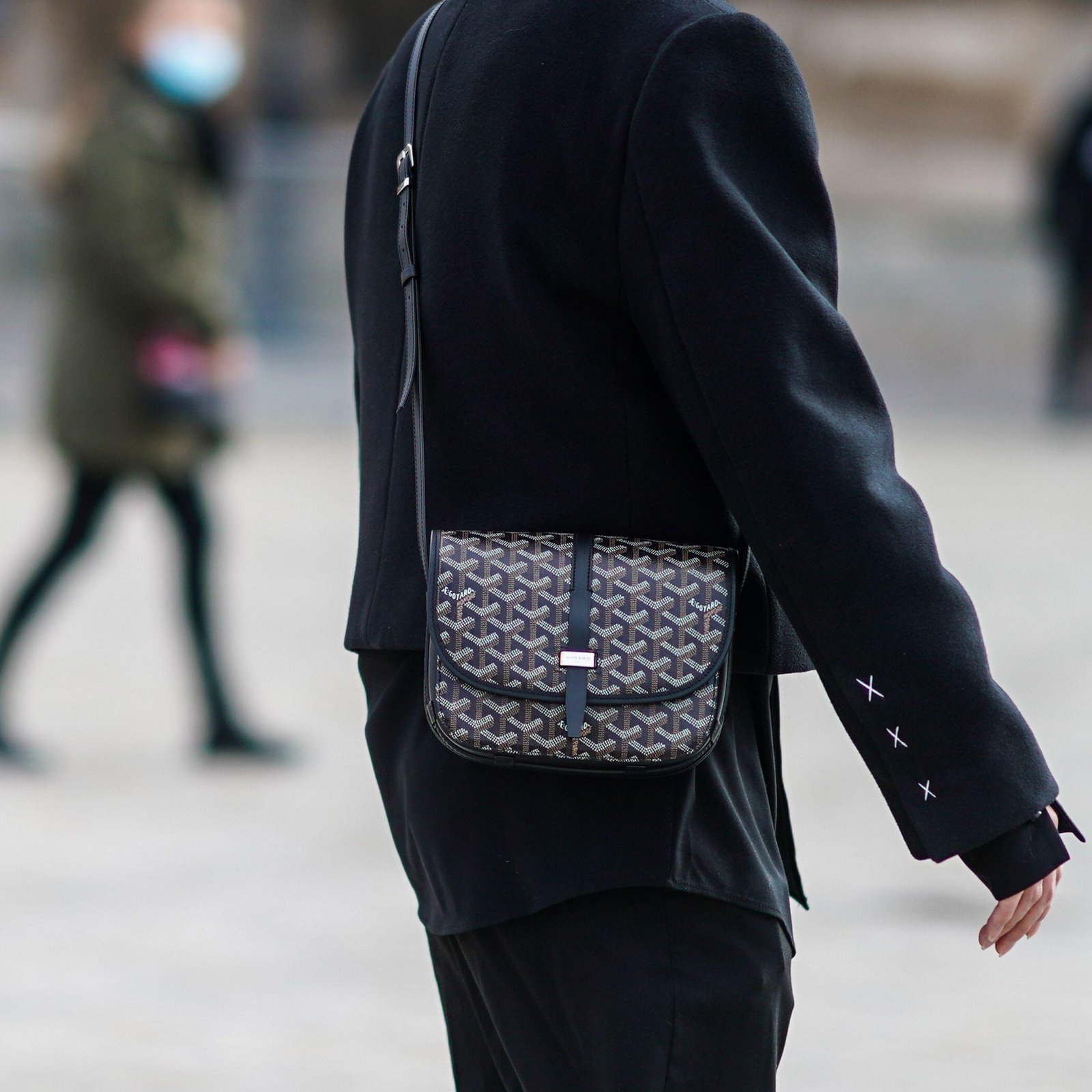 Goyard Belvédère PM bag worn crossbody with a dark tailored outfit.
