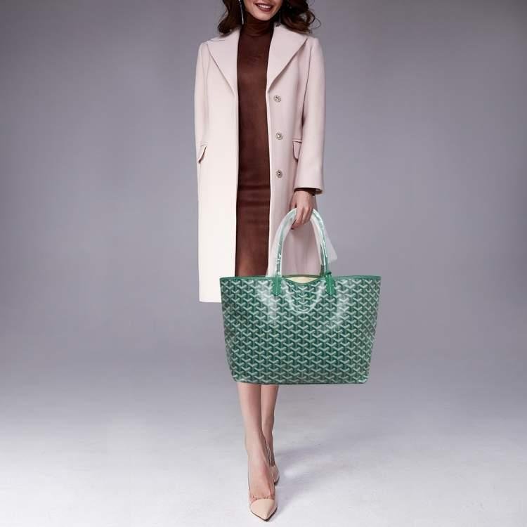 Woman carrying a green Goyard tote with a tailored neutral outfit.