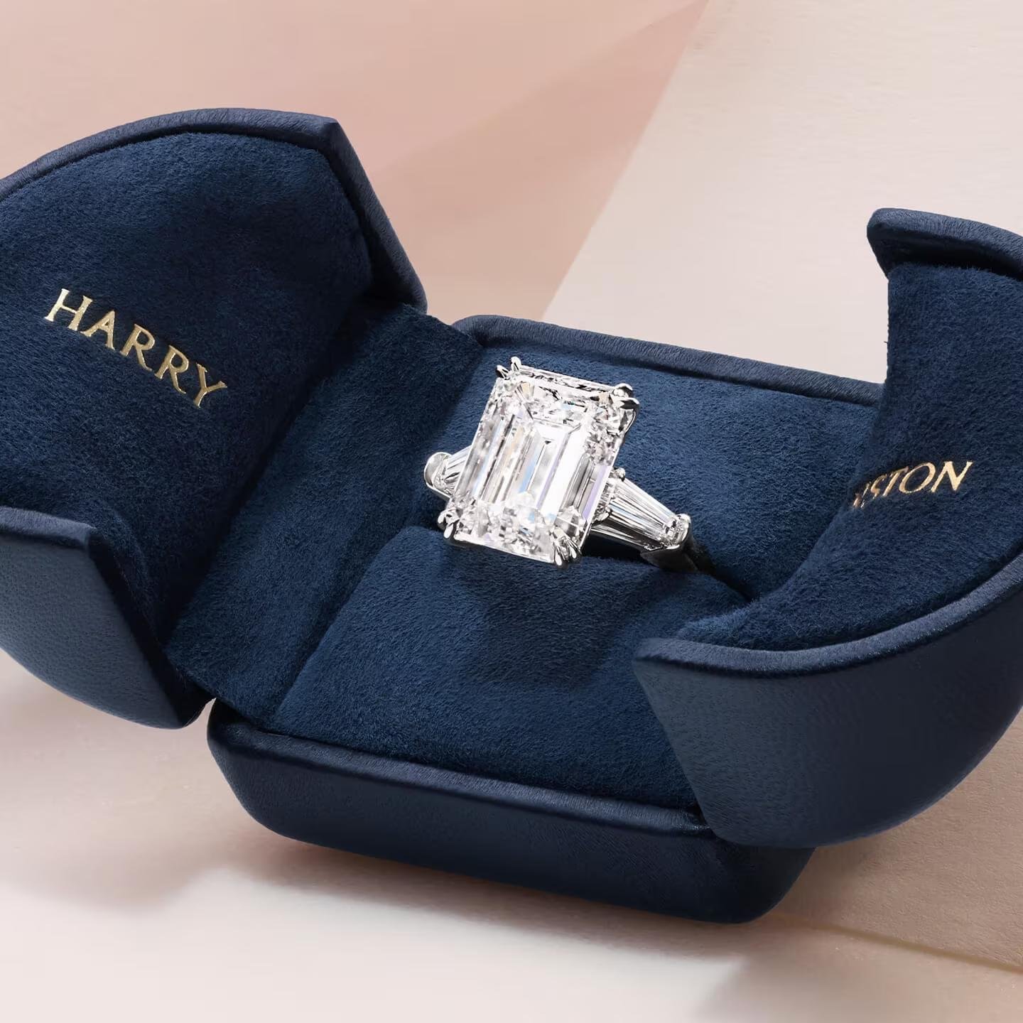Harry Winston emerald-cut engagement ring presented in a navy-blue box.