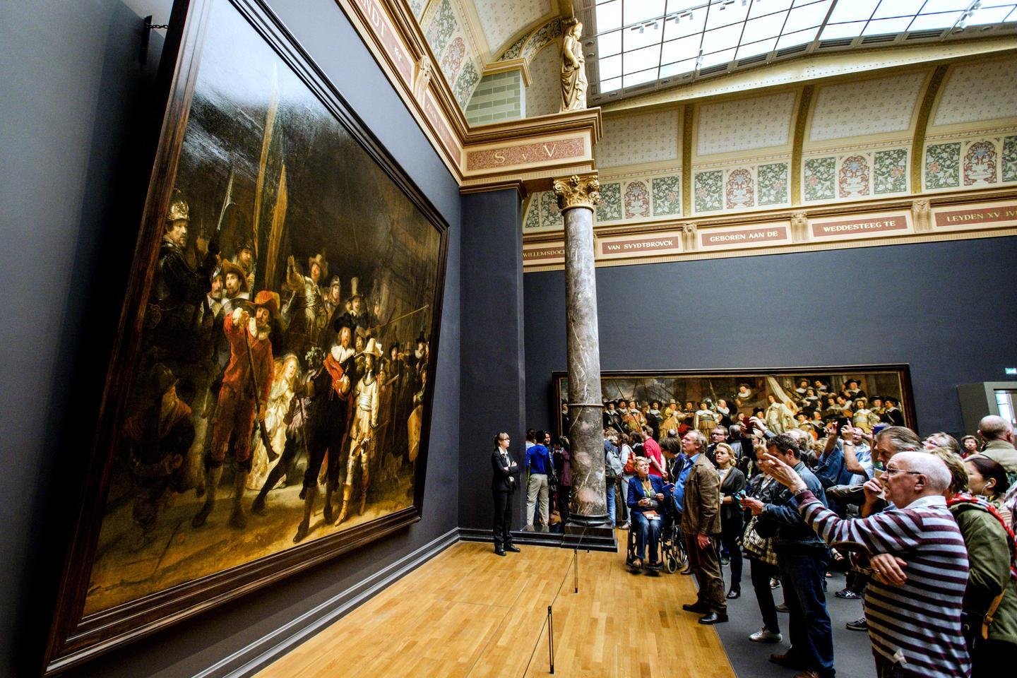 Visitors gathered around major paintings in the Rijksmuseum.