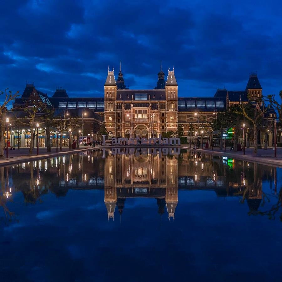 Rijksmuseum illuminated beside the water at night.